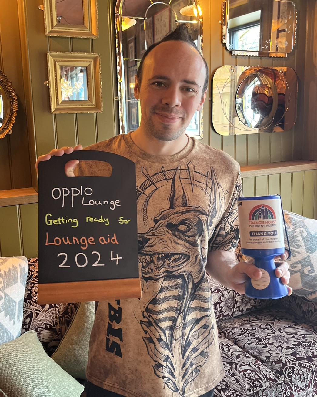 Man holding a charity collection tin and a chalk board stood in a restaurant