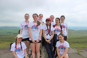 Group of girls wearing white t-shirts stood at the top of a hill