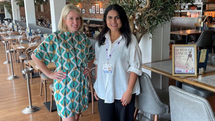 Two women stood in a restaurant in front of tables with an olive tree