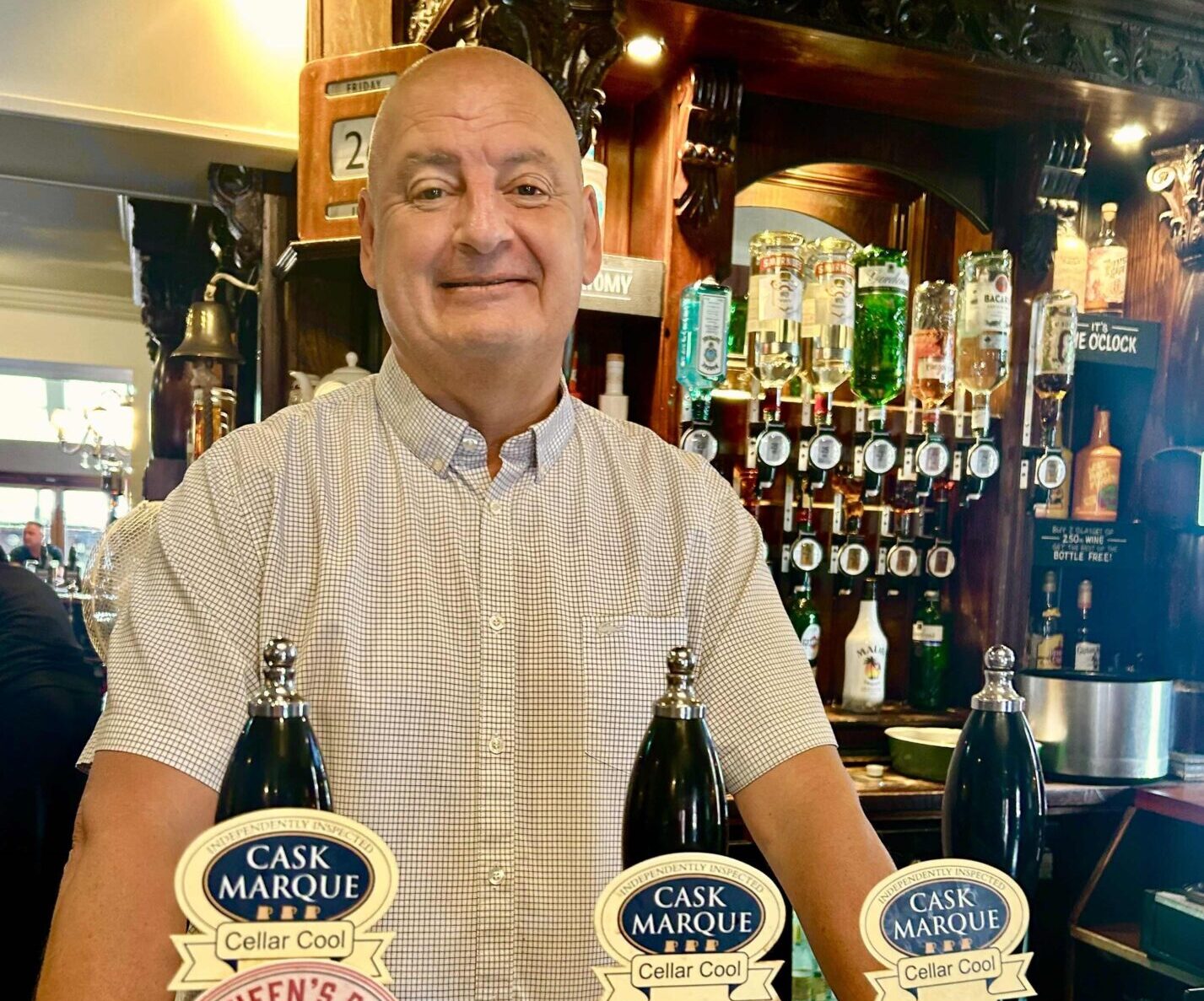 Man stood behind a bar infront of three beer pumps