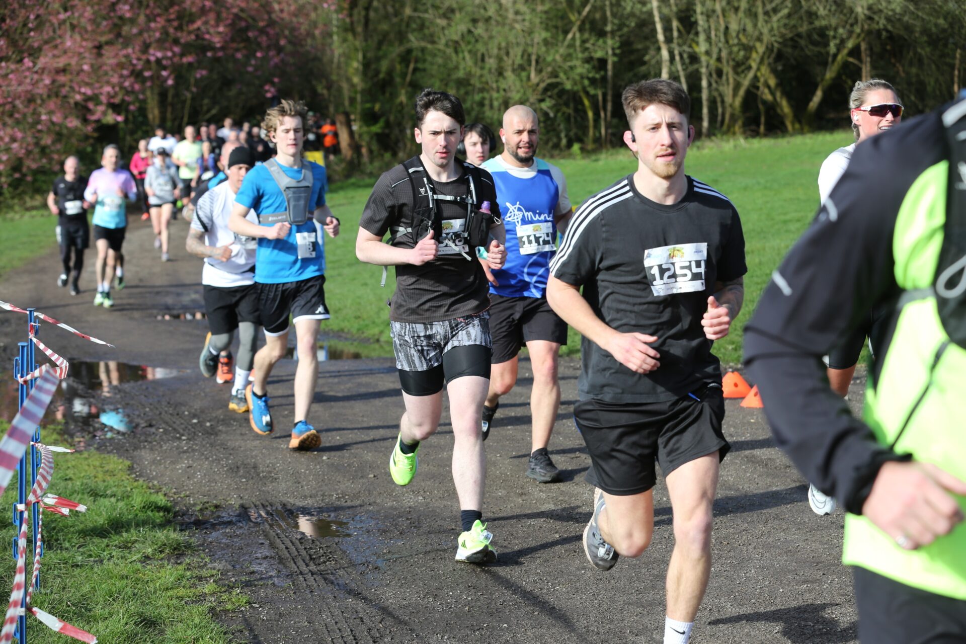 Several runners close together racing down a tarmac path on the Run Heaton Park course