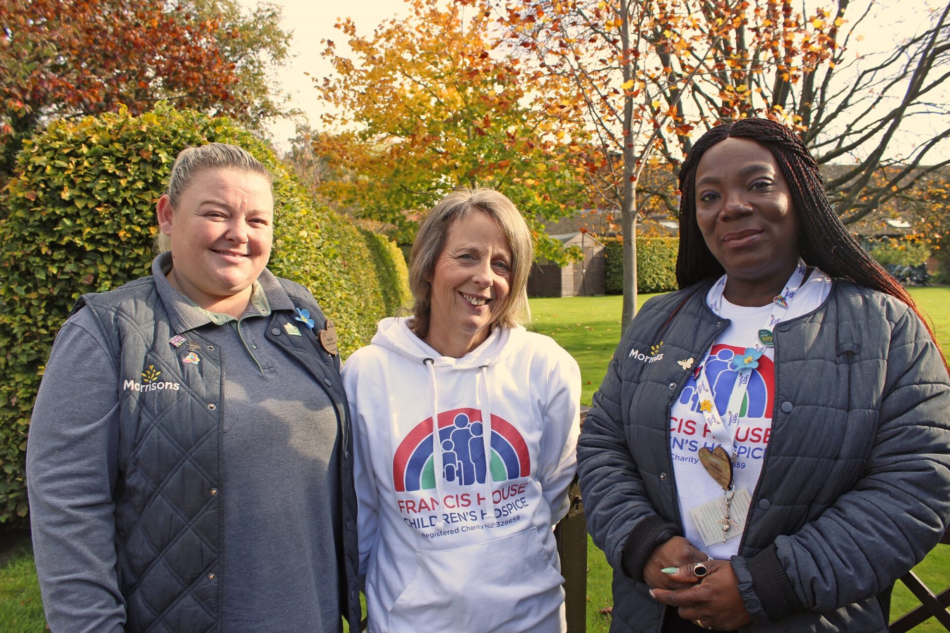 Three women wearing matching t-shirts stood in a garden